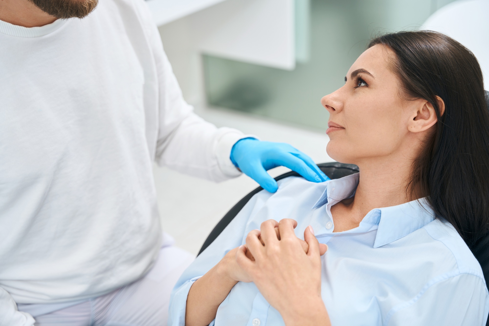 Male dentist calming down nervous woman patient before oral cavity check-up