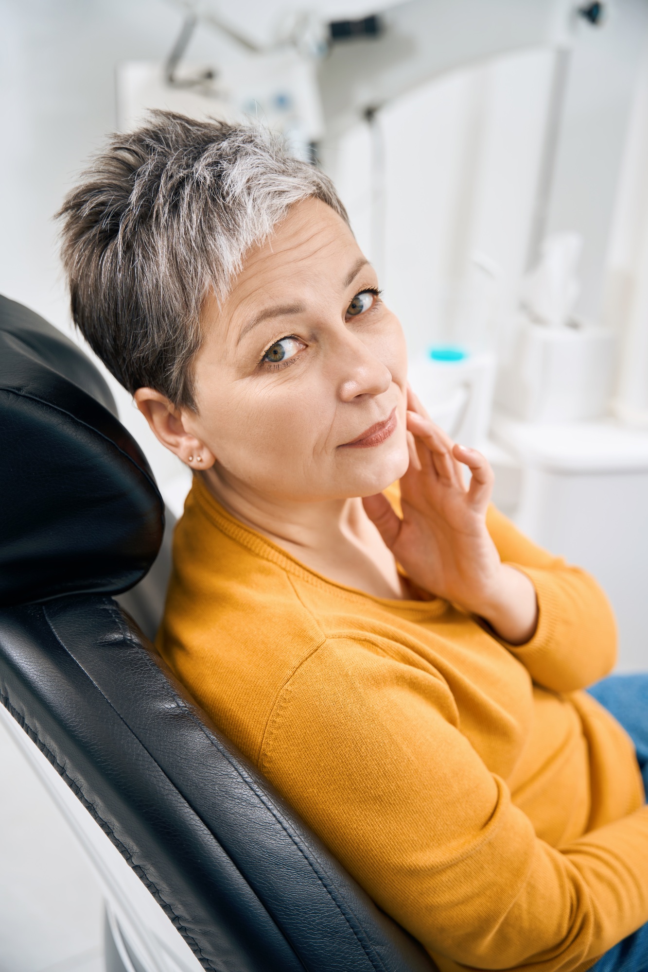 Senior woman touching sore cheek sitting on examination chair