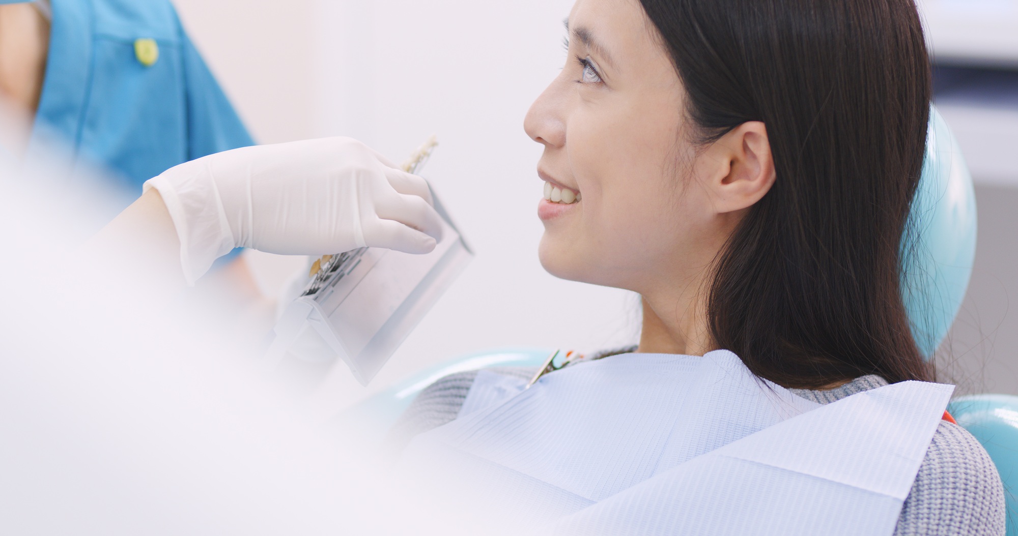 Smiling woman with palette for tooth color in dental clinic