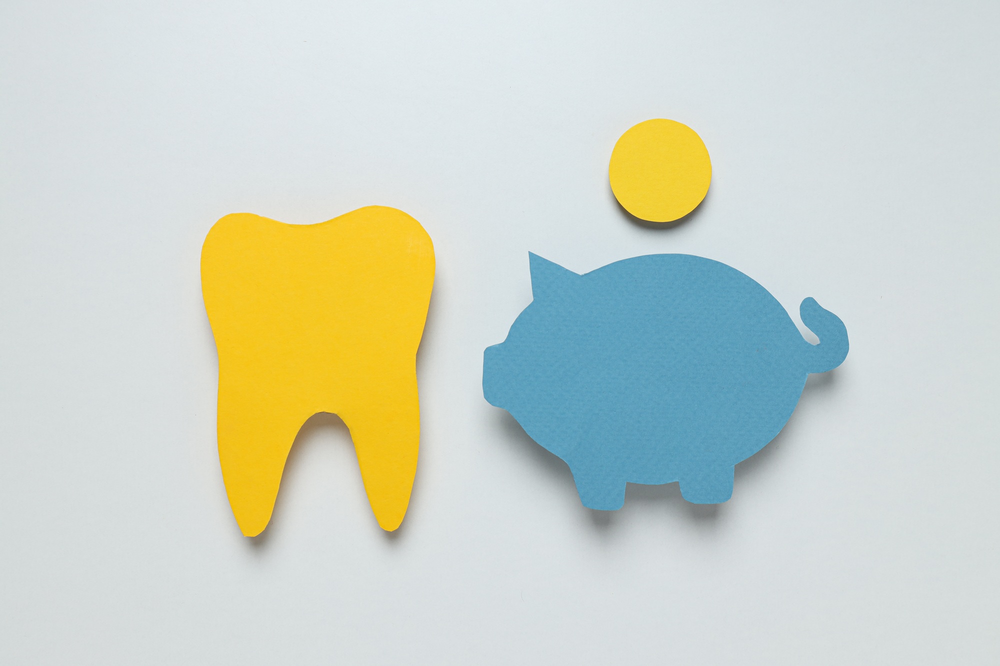 Paper tooth, piggy bank and coin on white background, top view